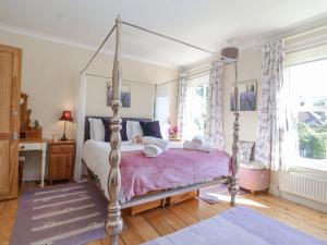 a bedroom with a canopy bed with a purple blanket at Green Gate Cottage in Southwold
