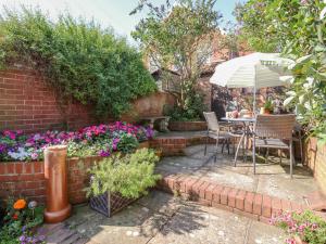 a garden with a table and chairs and flowers at Green Gate Cottage in Southwold