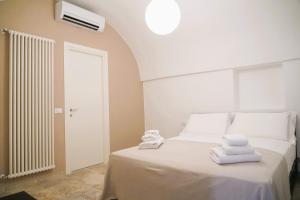 ein Schlafzimmer mit einem weißen Bett und Handtüchern darauf in der Unterkunft Palazzo Lorizzo - nel CUORE di OSTUNI in Ostuni