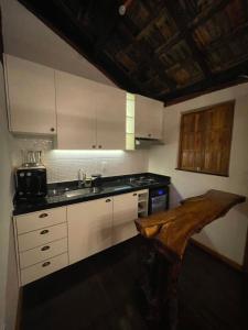 a kitchen with white cabinets and a wooden table at Chácara da Tuia in Estancia do Castello