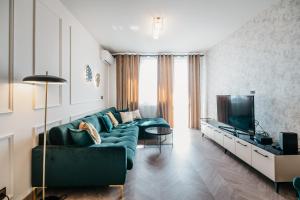 ein Wohnzimmer mit einem grünen Sofa und einem TV in der Unterkunft Nocosfera Apartament Premium Ogrodowy II in Kalisz