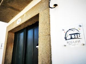 Una puerta a un edificio con un cartel. en ROSA XVI - Garden Guest House, en Vilar Torpim