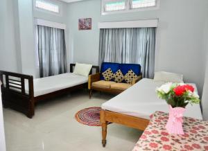 Namaskar Lodge and Homestay في غاواهاتي: غرفة معيشة بها سريرين وأريكة