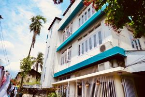 a white building with blue trim and a palm tree at Namaskar Lodge and Homestay in Guwahati