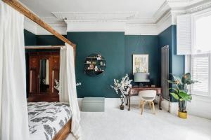 Charming 1 Bed London Flat في لندن: غرفة نوم بجدران زرقاء وسرير ومكتب