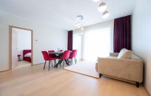 New apartment in Haabersti في تالين: غرفة معيشة مع أريكة وطاولة مع كراسي حمراء