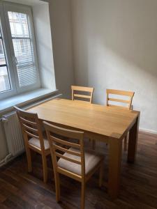 une table à manger en bois avec quatre chaises et une fenêtre dans l'établissement Apartmány u Arény Ostrava, à Ostrava