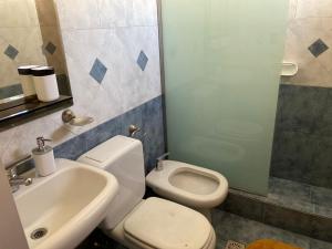 a bathroom with a white toilet and a sink at KAD Alojamiento in Mendoza