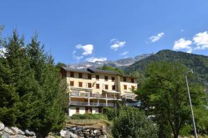 a building on a hill with mountains in the background at VAUJANYLOCATIONS - Roches Grandes 49 in Vaujany