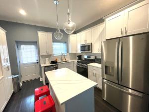 a kitchen with white cabinets and a stainless steel refrigerator at The Blue House! Modern+ Rooftop deck+ Parking in Baltimore