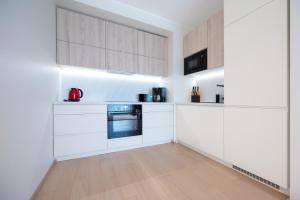 a kitchen with white cabinets and a wooden floor at New apartment in Haabersti in Tallinn