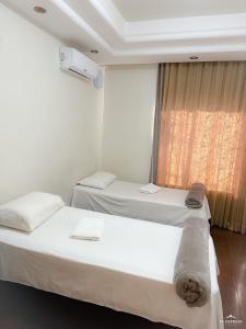 dwa łóżka w pokoju z oknem w obiekcie Pousada Vale do Rubi w mieście Londrina