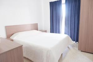 1 dormitorio con cama blanca y cortinas azules en Shamrock Apartments, en St Paul's Bay 15 fotos más