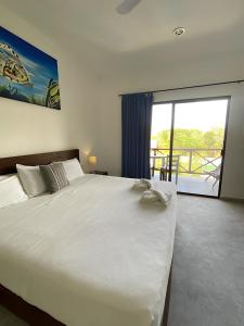 a bedroom with a large white bed and a balcony at Basic Tulum in Tulum