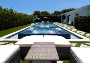 a swimming pool with a table and a bench in a yard at House Of Art - Luxury Villa with Pool & Jacuzzi! in Tamiami