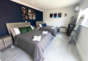 two beds in a bedroom with blue walls at House Of Art - Luxury Villa with Pool & Jacuzzi! in Tamiami