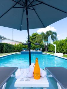 a table with glasses and an umbrella next to a swimming pool at House Of Art - Luxury Villa with Pool & Jacuzzi! in Tamiami