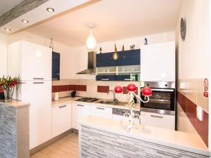 una cocina con armarios blancos y bolas rojas en la encimera en Spacious apartment with private terrace, en Pridvorje