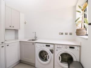 a white laundry room with a washer and dryer at Suncroft in Cheltenham