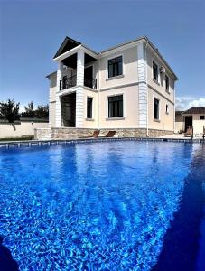 a house with a large swimming pool in front of it at Qafqaz Manor Napoli in Gabala