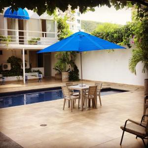 a table with a blue umbrella next to a pool at Hotel Casa Victoria Rodadero Reservado in Gaira