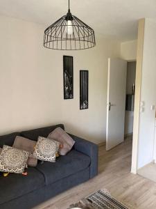 ein Wohnzimmer mit einem blauen Sofa und einem hängenden Licht in der Unterkunft Studio au cœur de chatelguyon in Châtel-Guyon + 45 Fotos