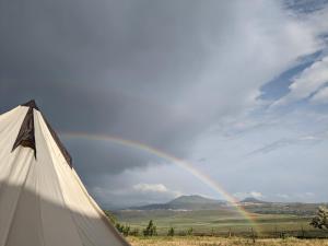 un arco iris en el cielo con un tipi en Campy Mountain Campsite, en Tkhit