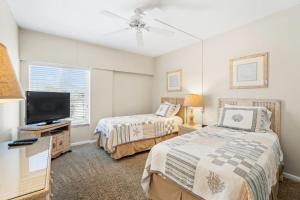 een slaapkamer met 2 bedden en een flatscreen-tv bij Island House Beach Resort 13S in Point O'Rocks