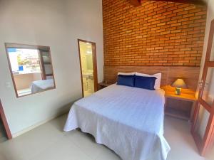 ein Schlafzimmer mit einem Bett mit blauen Kissen und einem Spiegel in der Unterkunft 020A - Sobrado de 3 quartos para alugar, Bombinhas/SC in Bombinhas + 19 Fotos