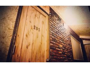 a wooden door with the number on a brick wall at Guest House Garage IMAZU - Vacation STAY 15208 in Takashima