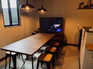 a dining room with a wooden table and a tv at Guest House Garage IMAZU - Vacation STAY 15208 in Takashima