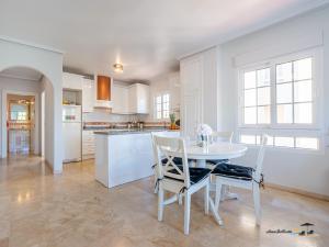 a white kitchen with a white table and chairs at CASA DE FLAMENCO in Orihuela Costa