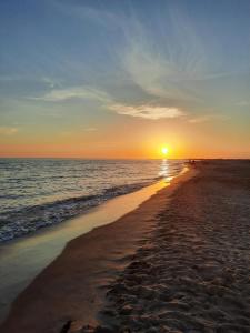 una spiaggia con il sole che sorge sull'oceano di L'oiseau bleu a Salin-de-Giraud