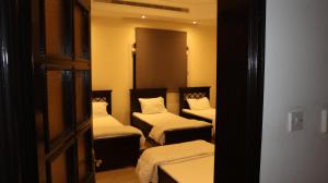 Habitación con 3 camas y sábanas blancas. en International Abu Dhabi Hostel, en Abu Dabi