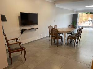ein Esszimmer mit einem Tisch, Stühlen und einem TV in der Unterkunft La maison de Solange in Esquelbecq