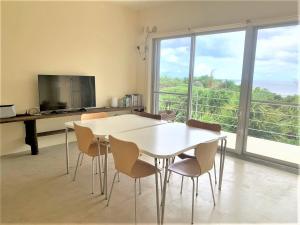ein Esszimmer mit Tisch und Stühlen und einem großen Fenster in der Unterkunft Blue cave Blue in Green - Vacation STAY 31673v in Fukai