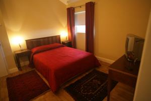 a bedroom with a red bed and a television at Pateo do Morgado - Turismo de Habitacao in Casa Branca
