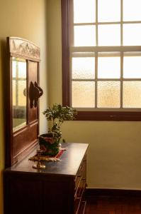 uma mesa com um vaso de planta ao lado de uma janela em - Casa Pitanga - Acomodação lindíssima pertinho da Igreja do Rosário em Ouro Preto