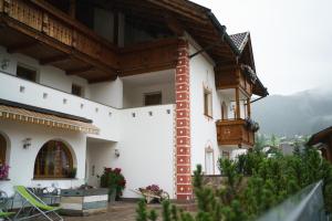 a large white building with a balcony and a table at Garni Hotel Belalp in Santa Cristina Gherdëina