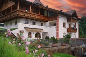 a large white house with a wooden roof at Garni Hotel Belalp in Santa Cristina Gherdëina