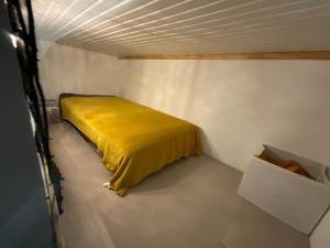 1 dormitorio con 1 cama amarilla en una habitación blanca en Charmant T2 3 Lits 4 personnes et 1enfant 55m2 parking et terrasse, en Saint-Sever