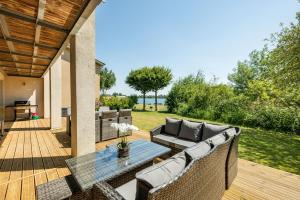 un patio avec un canapé et une table sur une terrasse dans l'établissement Lakeside property with spa on a nature reserve Butterfly Sound CW10, à Somerford Keynes