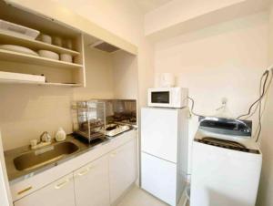 a kitchen with a white refrigerator and a microwave at SunStay Fudomae 1 - Vacation STAY 35591v in Tokyo
