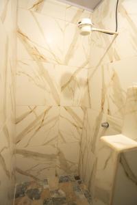 a bathroom with a shower with a marble wall at Apartamento Quepoa in Quepos