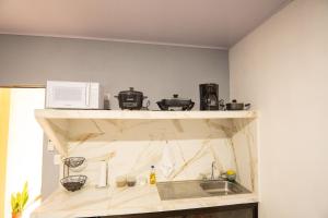 a kitchen with a sink and a microwave on a shelf at Apartamento Quepoa in Quepos