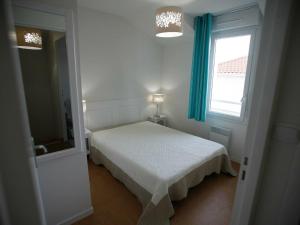 a white bedroom with a bed and a window at Holiday Home with terrace at 600 m from beach in Saint-Brévin-lʼOcéan