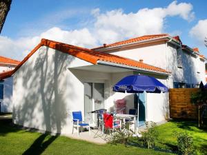 a small white house with a table and an umbrella at Holiday Home with terrace at 600 m from beach in Saint-Brévin-lʼOcéan