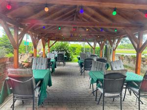un patio al aire libre con mesas verdes, sillas y luces en Hotel Zéta, en Lenti