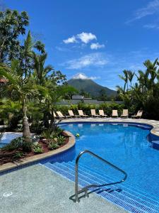 a swimming pool with chairs and a mountain in the background at Hotel Boutique Casa Del Rio in Fortuna