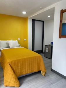 1 dormitorio con cama amarilla y pared amarilla en Hotel Renovación, en Caracas